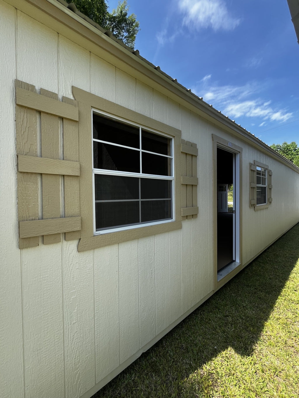 Outland Trailers 14x40 tiny home shell with wooden exterior and large windows, ready for customization and interior finishing.
