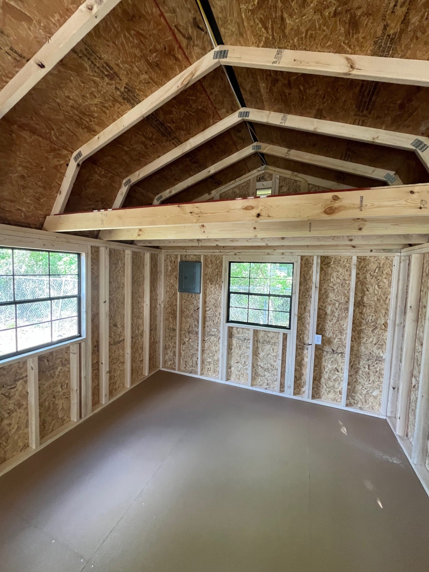 Outland Trailers 12x32 lofted barn cabin with raised roof, windows, and wooden exterior, showcasing a sturdy outdoor structure.