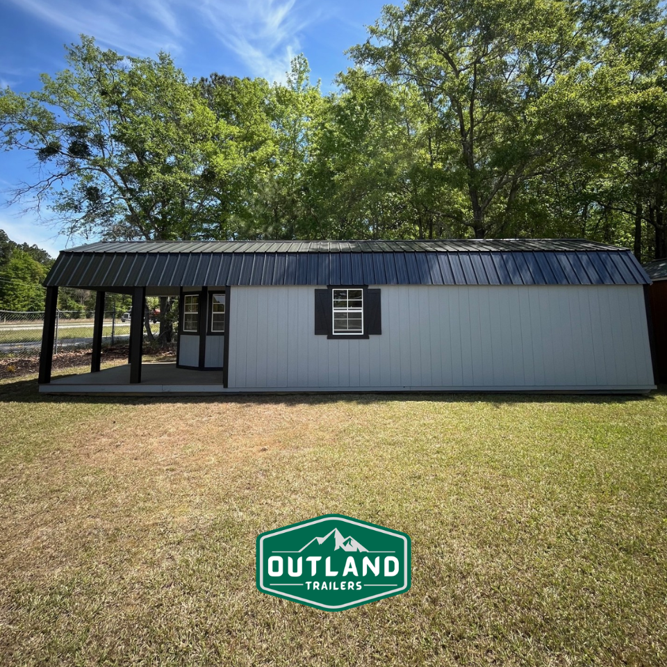 Outland Trailers 12x40 Deluxe Lofted Barn with wooden siding, lofted roof, and large front door for storage and outdoor use