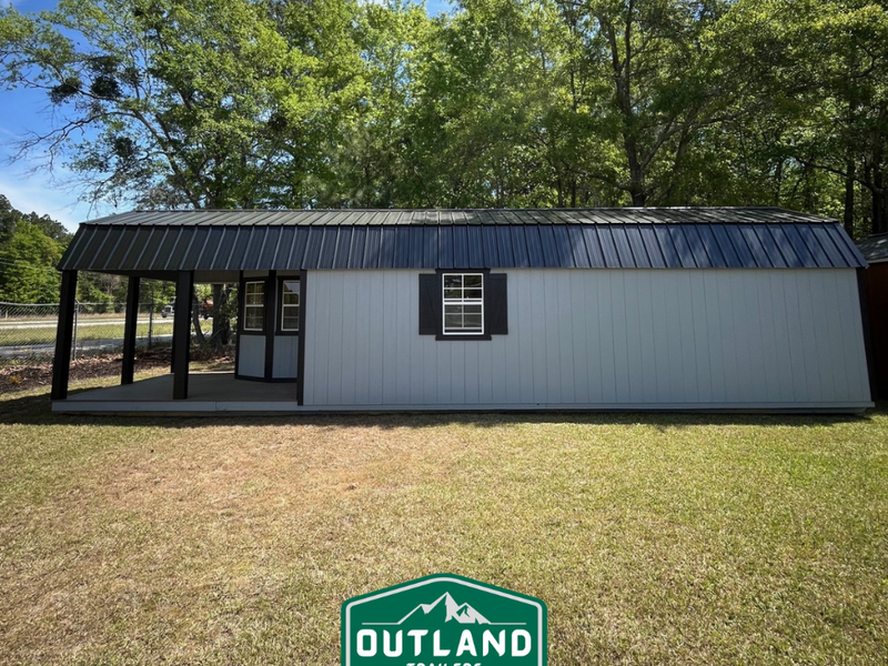 Outland Trailers 12x40 Deluxe Lofted Barn with wooden siding, lofted roof, and large front door for storage and outdoor use