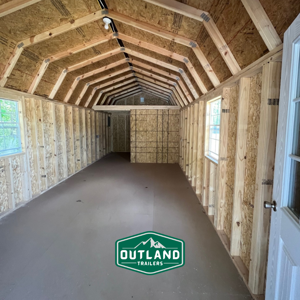 Outland Trailers 12x40 Deluxe Lofted Barn with wooden siding, lofted roof, and double doors, suited for storage or workshop use.