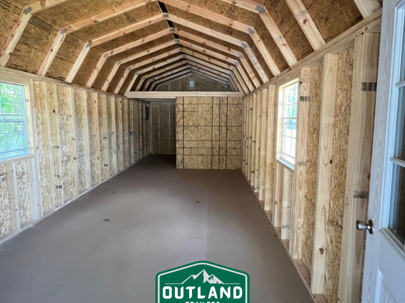 Outland Trailers 12x40 Deluxe Lofted Barn with wooden siding, lofted roof, and double doors, suited for storage or workshop use.