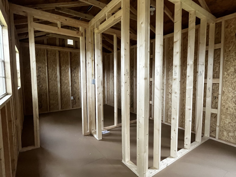 Outland Trailers 12x36 tiny home shell with wooden exterior and large front window, ready for customization and interior finishing.