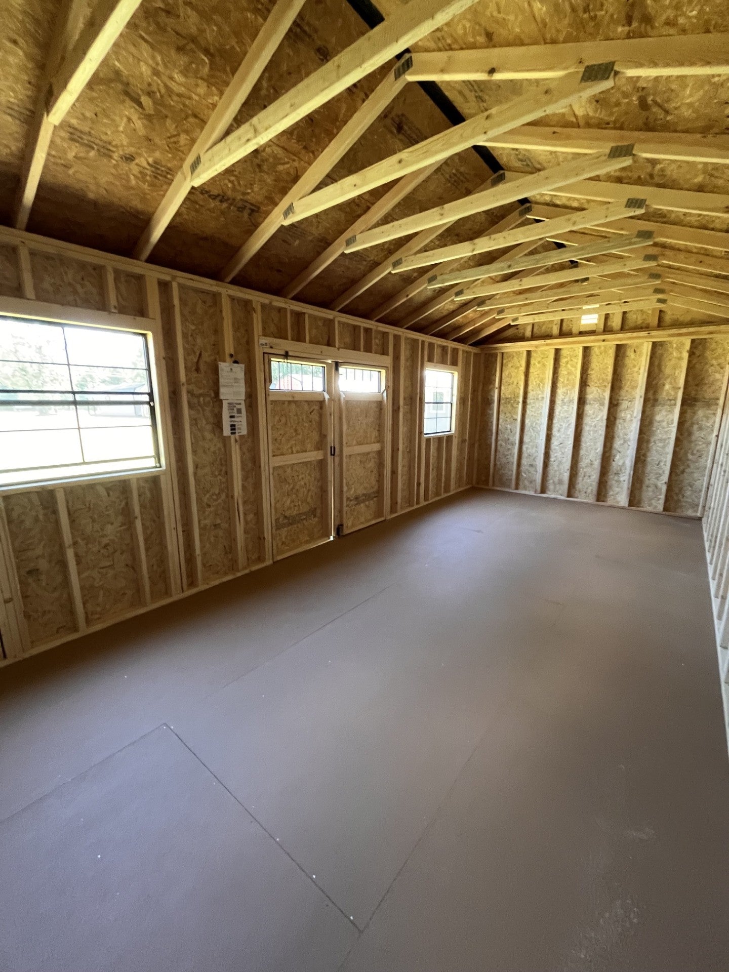 Outland Trailers 12x24 side utility shed with metal walls and door, outdoor storage solution in a backyard setting