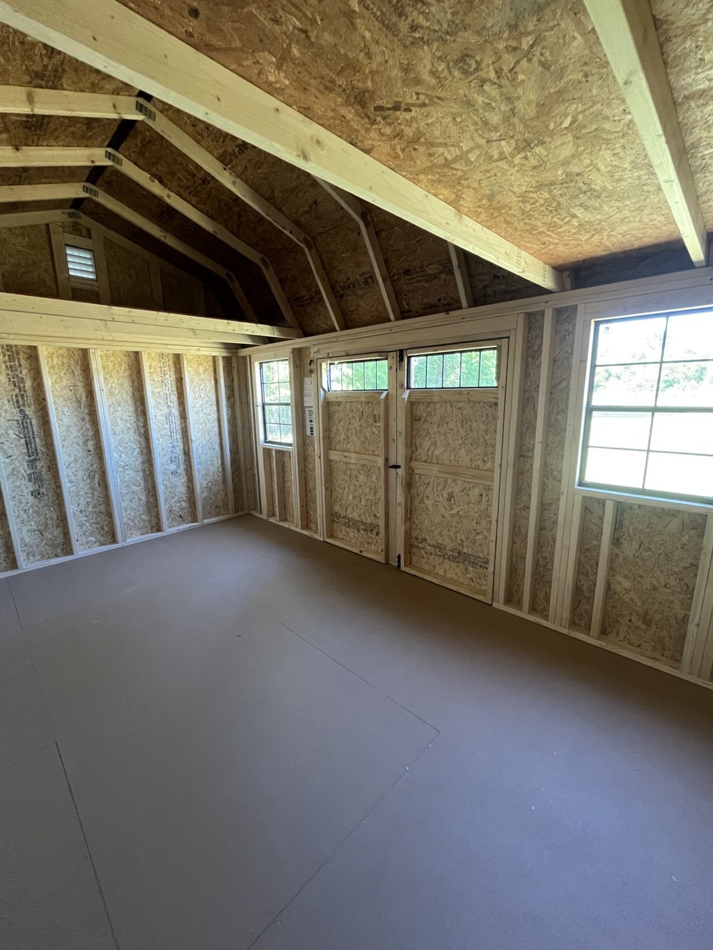 Outland Trailers 10x16 side lofted barn shed with double doors and side windows, showcasing durable wooden construction.