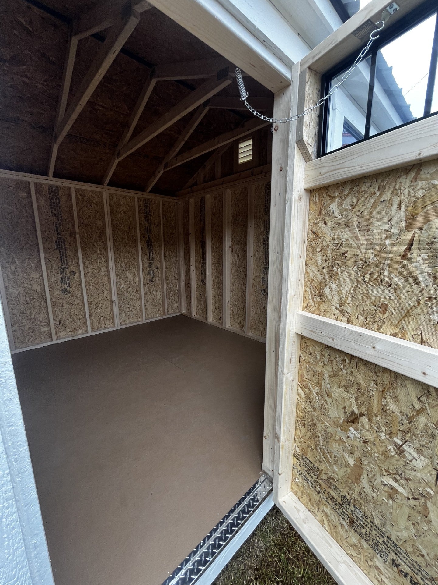 Outland Trailers 10x16 garden shed with double doors and window, made of durable wood for outdoor storage and organization.