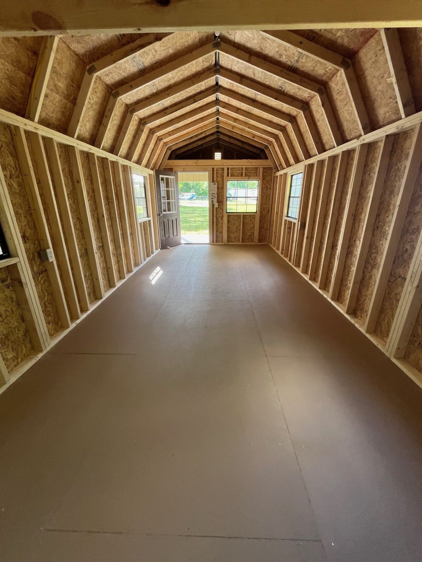 Outland Trailers 12x32 lofted barn cabin with wooden exterior, large windows, and lofted roof, suitable for storage or rustic retreat.