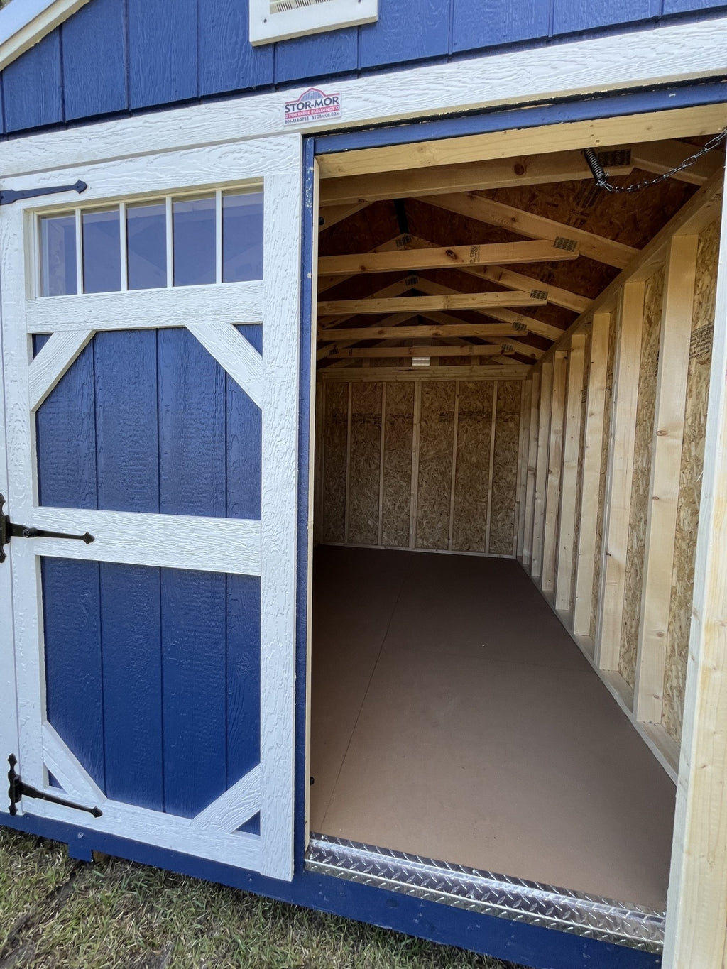 Outland Trailers 8x12 garden shed with double doors and weather-resistant wood exterior for outdoor storage.