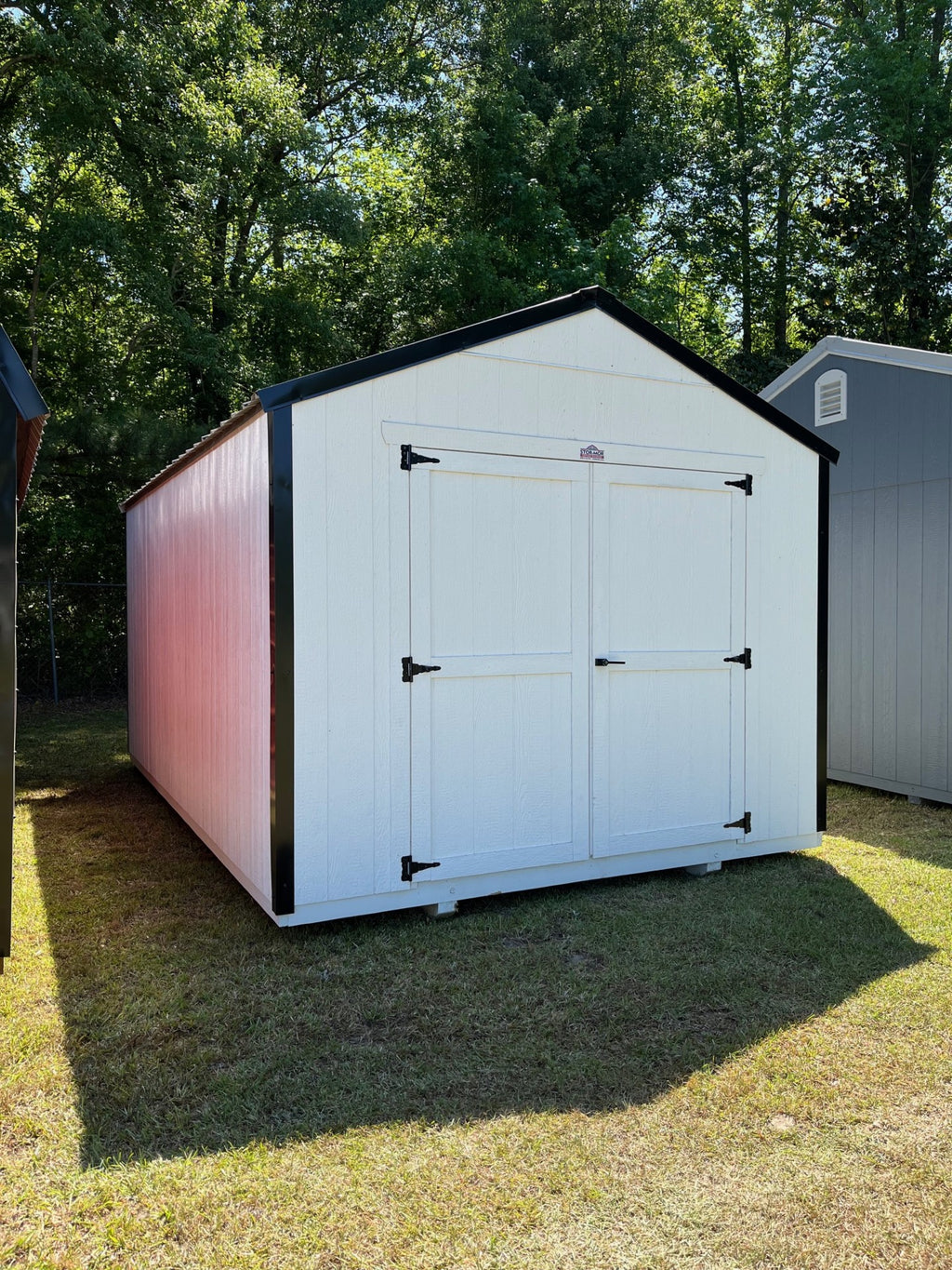 Outland Trailers 10x16 Tru-Valu Utility Shed with metal walls and double doors, shown in a backyard setting.