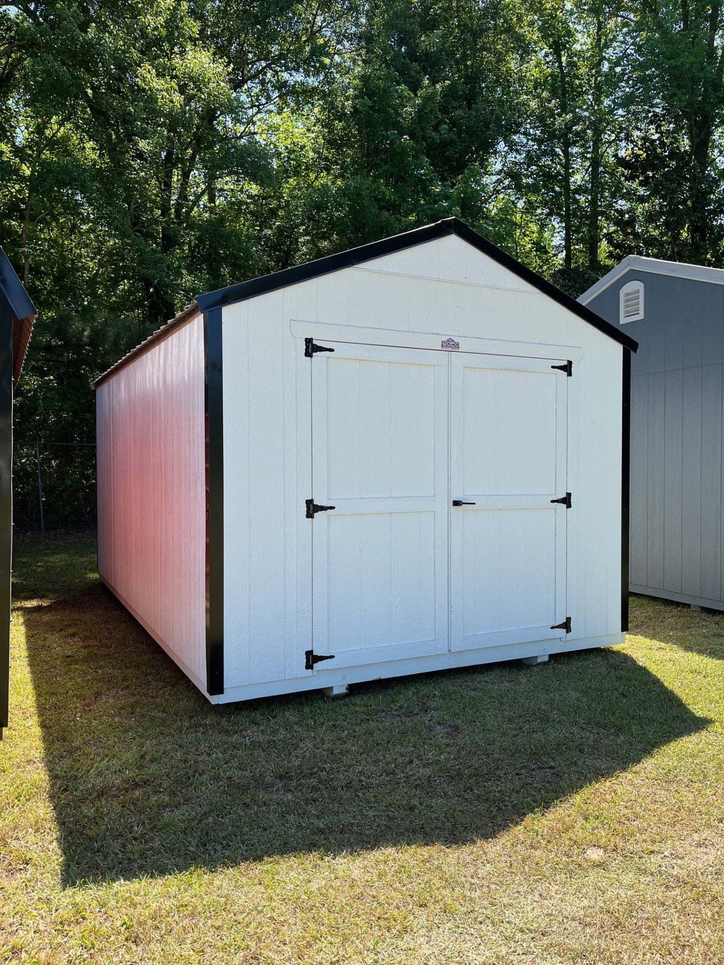 Outland Trailers 10x16 Tru-Valu Utility Shed with metal walls and double doors, shown in a backyard setting.