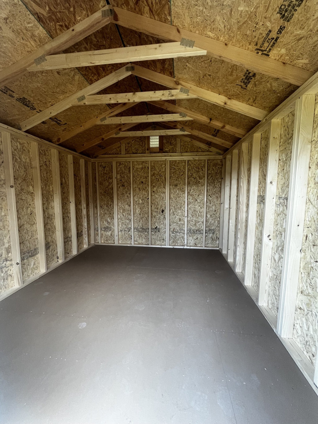 Outland Trailers 10x12 utility shed with metal roof and double doors, ideal for storage and outdoor equipment.