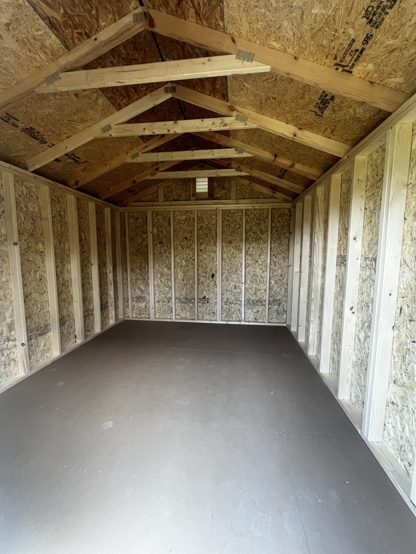 Outland Trailers 10x12 utility shed with metal roof and double doors, ideal for storage and outdoor equipment.