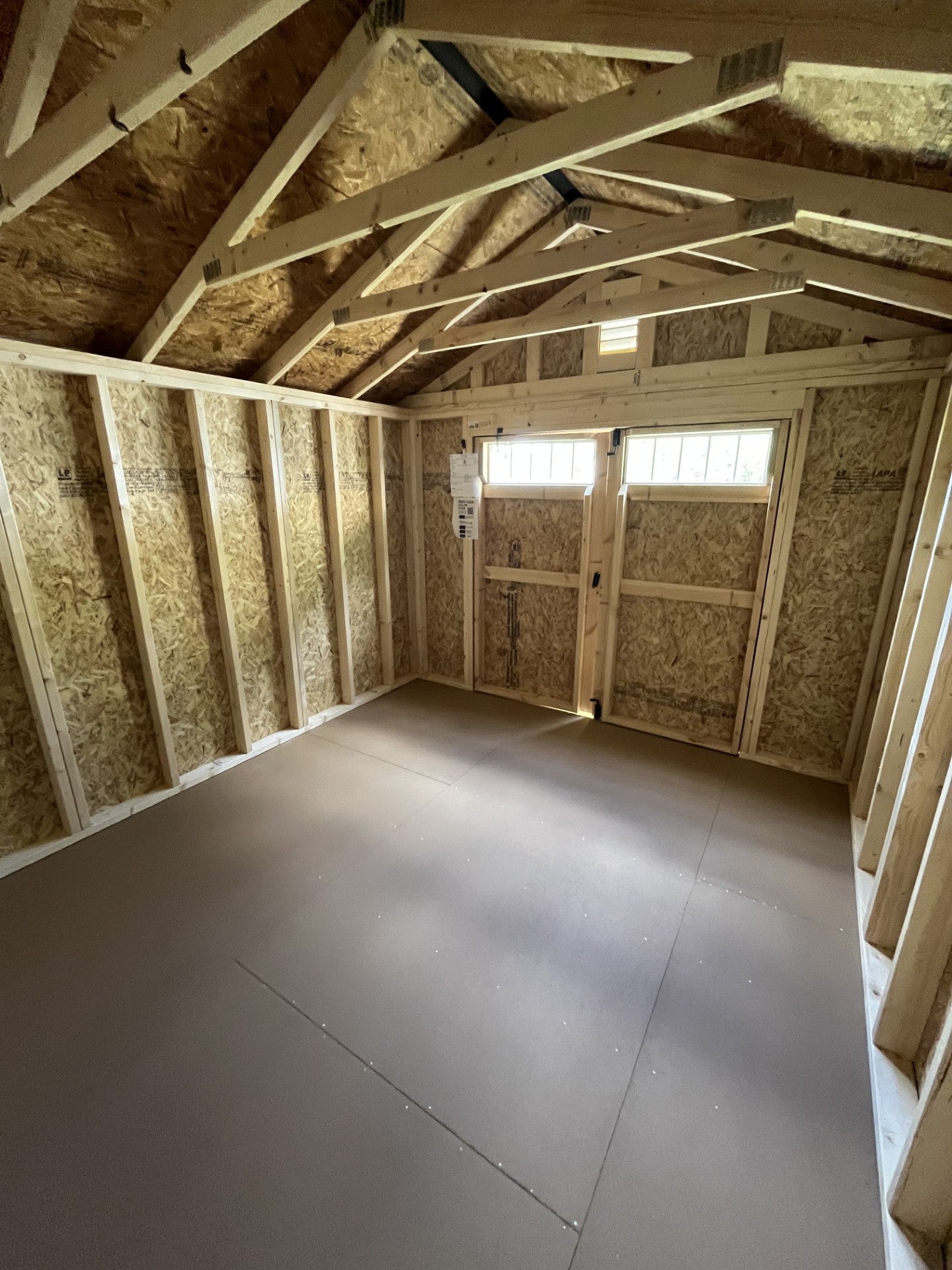 Outland Trailers 10x12 garden shed with double doors, weather-resistant construction, and sturdy wooden panels for outdoor storage.