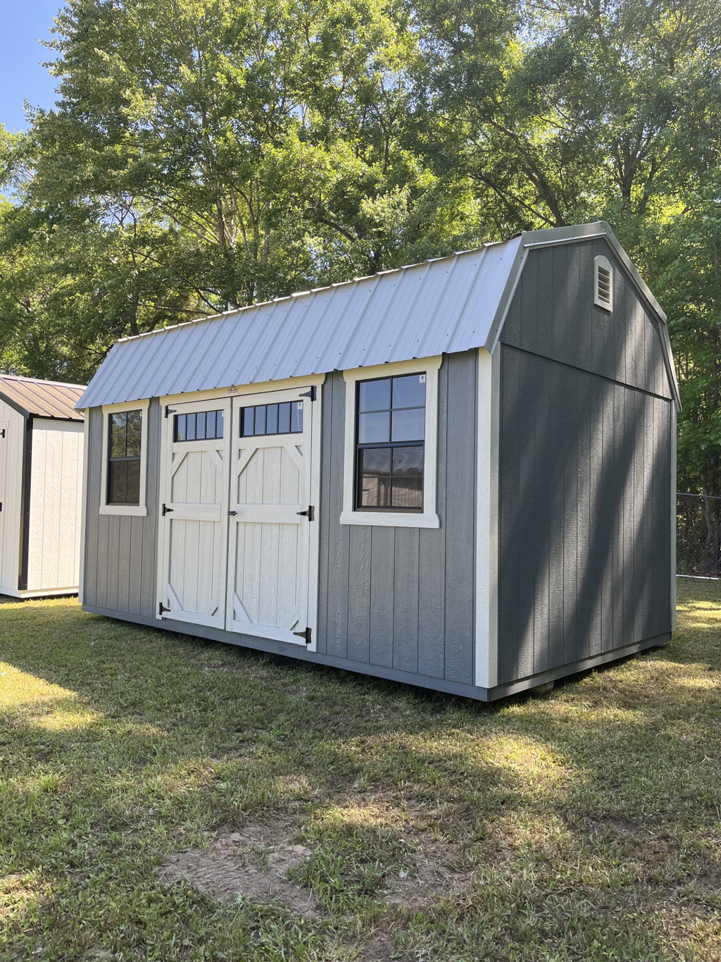 Outland Trailers 10x16 side lofted barn with wooden walls, side door, and lofted roof, suitable for storage or workshop use.