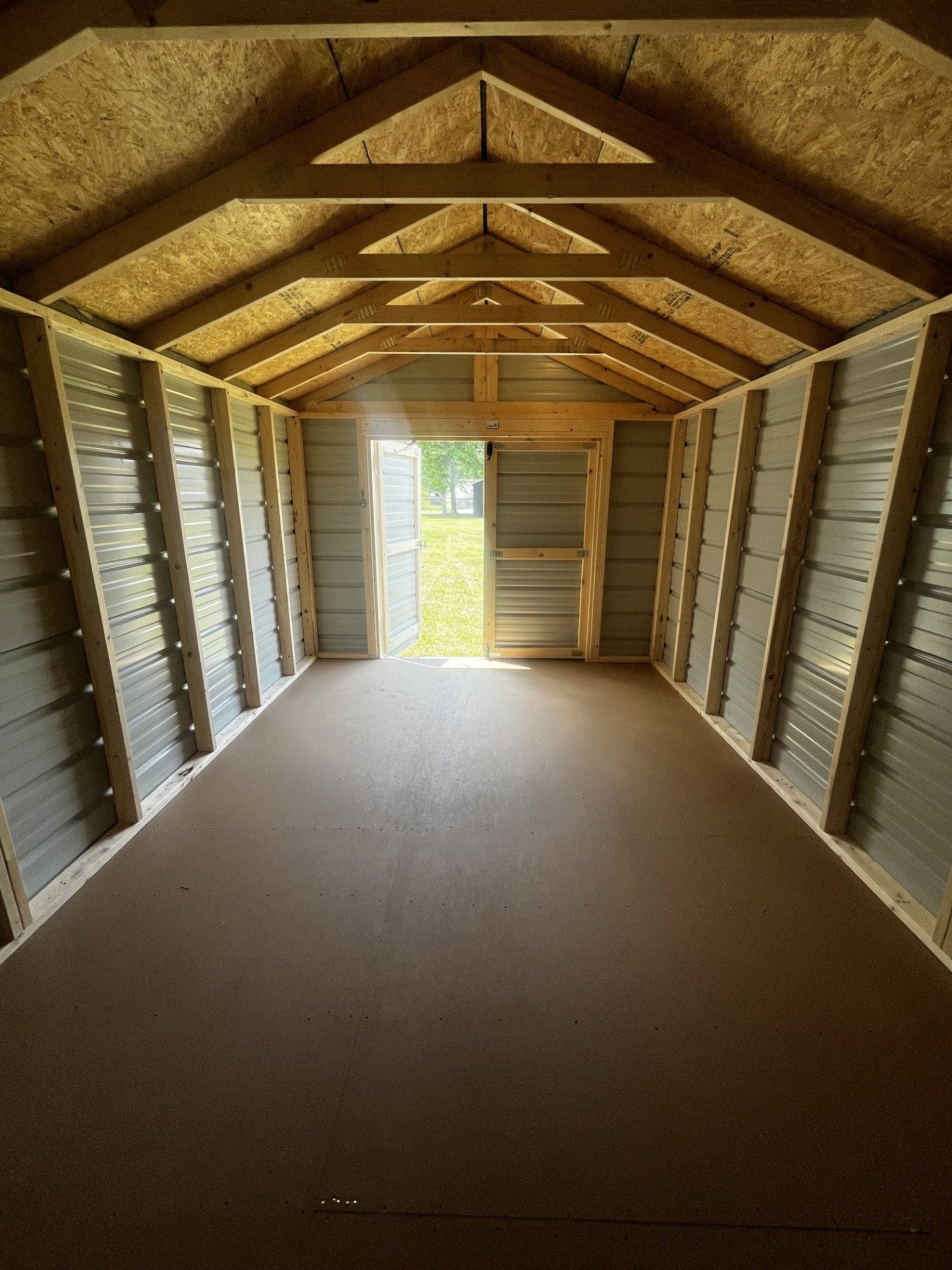 Outland Trailers 10x16 metal utility shed with double doors and vented roof, ideal for outdoor storage and garden tools.