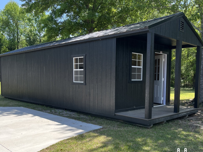 Outland Trailers 12x36 cabin trailer with wooden exterior and metal frame, ideal for camping or mobile tiny home use.