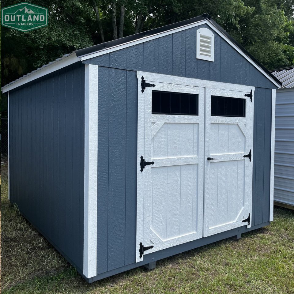 Outland Trailers 10x12 utility shed made of durable metal, with a peaked roof and side door for storage and organization.