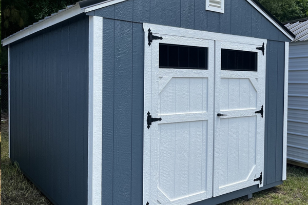 Outland Trailers 10x12 utility shed made of durable metal, with a peaked roof and side door for storage and organization.