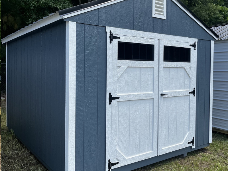 Outland Trailers 10x12 utility shed made of durable metal, with a peaked roof and side door for storage and organization.