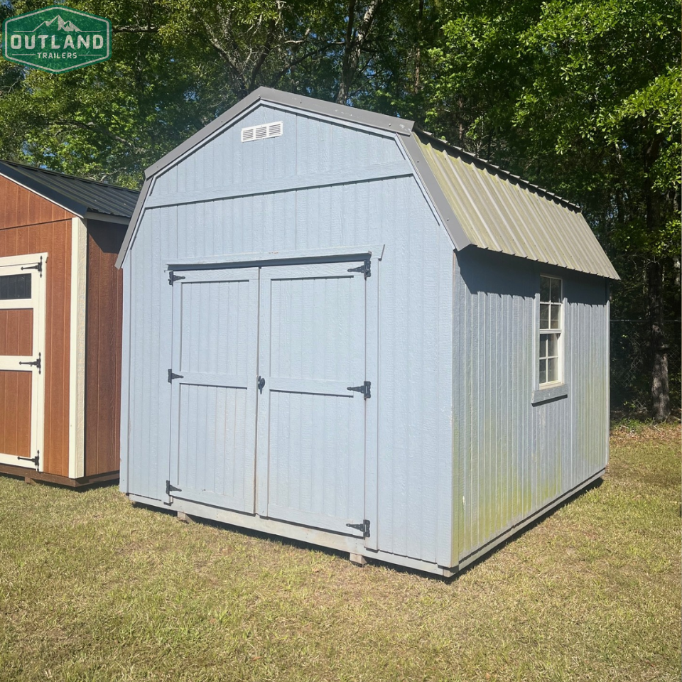 Used 10x12 lofted barn by Outland Trailers, showing the wooden structure with raised loft area and sturdy construction.