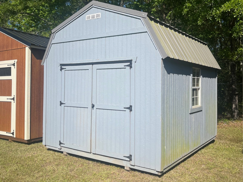 Used 10x12 lofted barn by Outland Trailers, showing the wooden structure with raised loft area and sturdy construction.