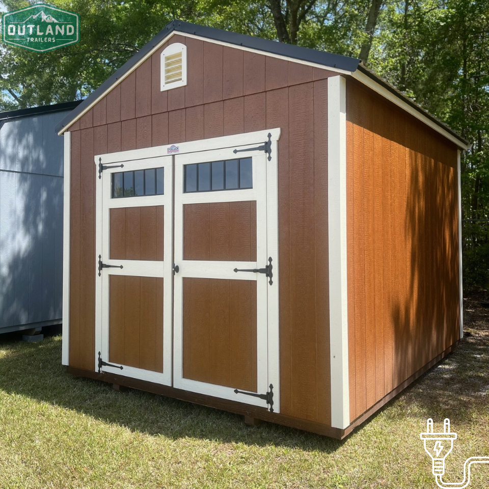 Outland Trailers 10x12 utility shed with wooden door and metal roof, ideal for storage and outdoor use.