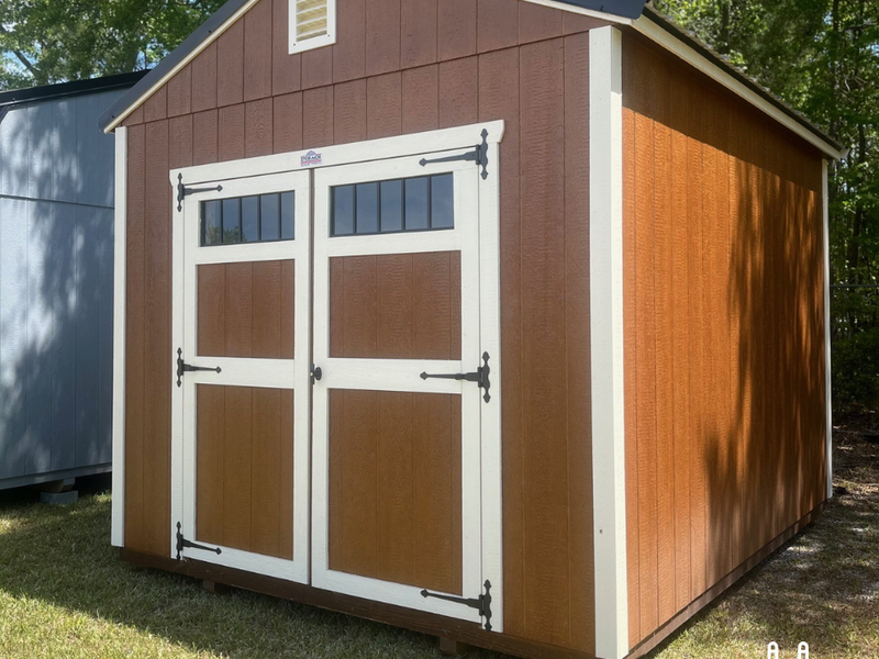 Outland Trailers 10x12 utility shed with wooden door and metal roof, ideal for storage and outdoor use.