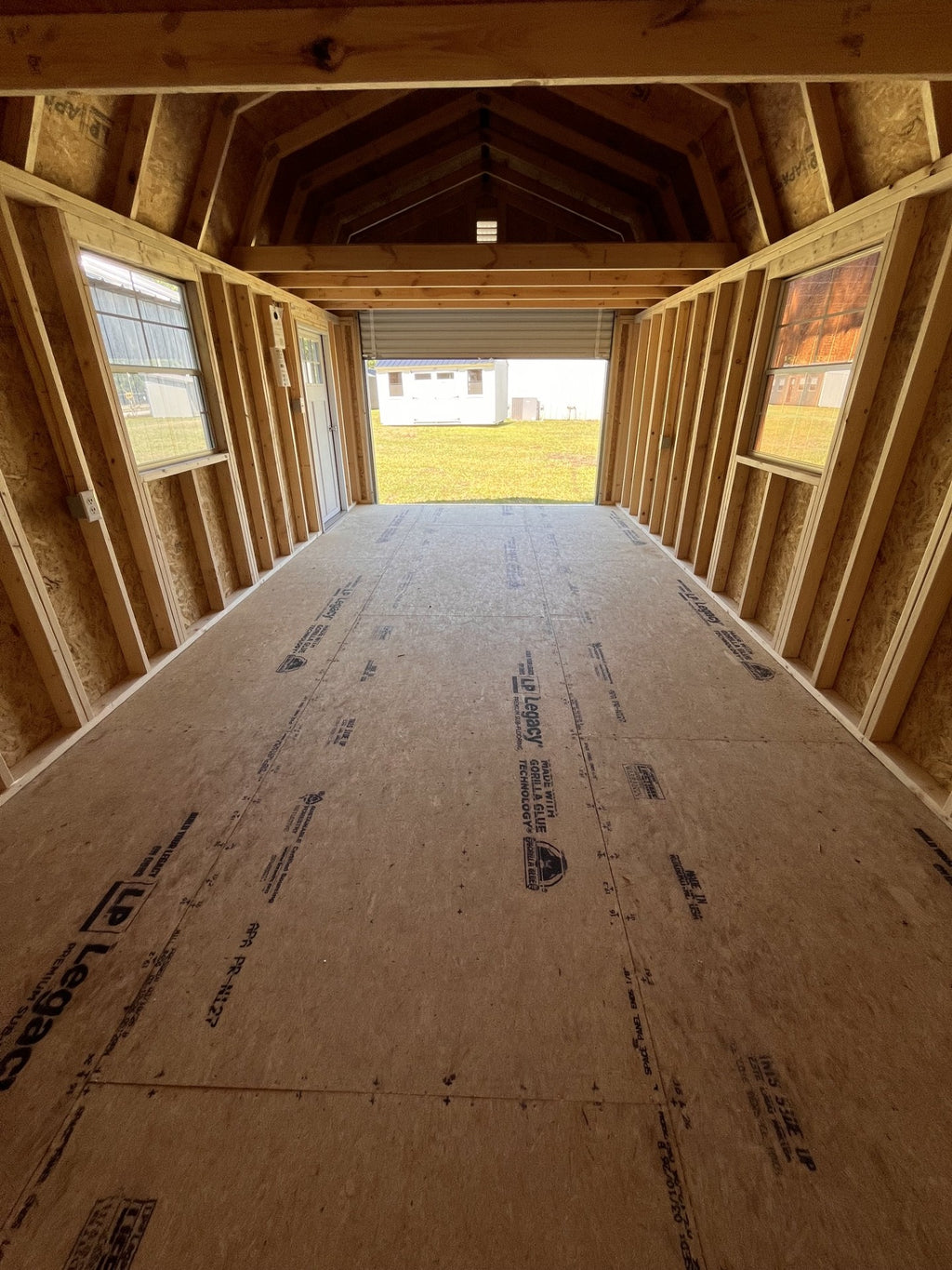 Outland Trailers 12x24 lofted garage with metal siding and a side door, showcasing its spacious design and sturdy construction.