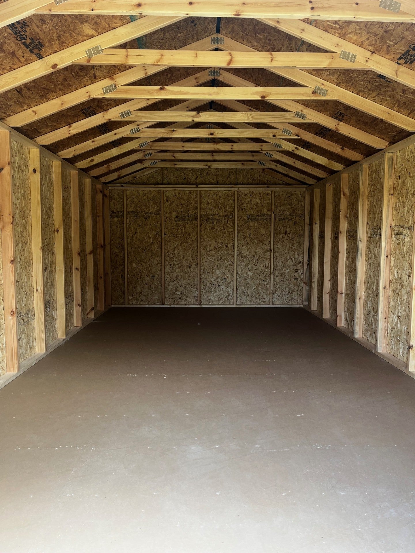 Outland Trailers 12x20 utility shed with metal walls and a single door, suitable for storage and outdoor use.