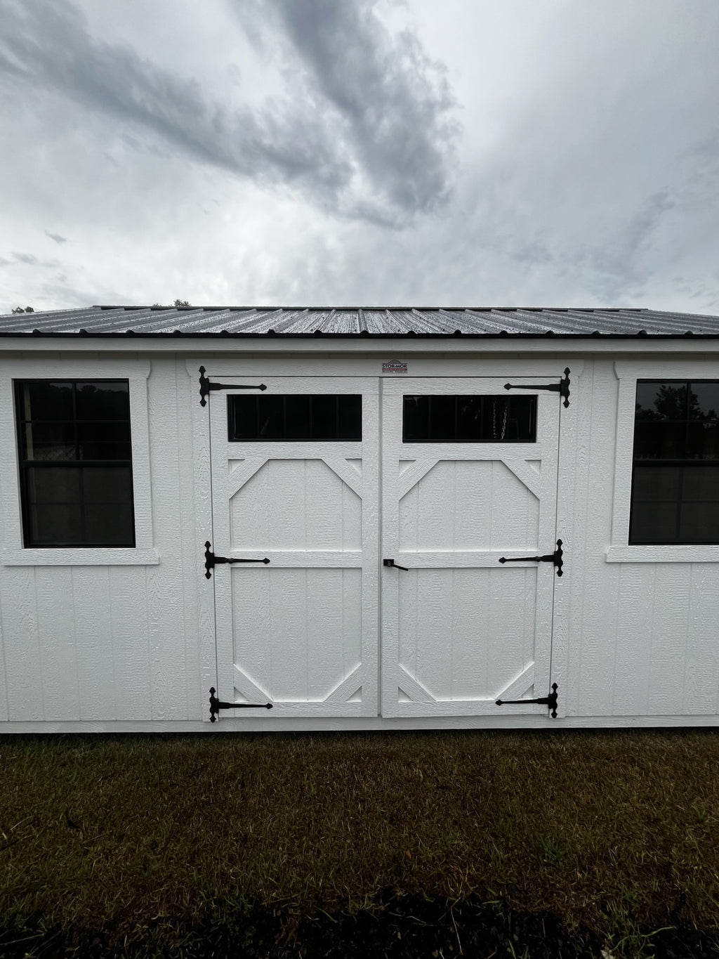 Outland Trailers 10x16 garden shed with durable metal walls and a gable roof, ideal for outdoor storage and gardening tools.
