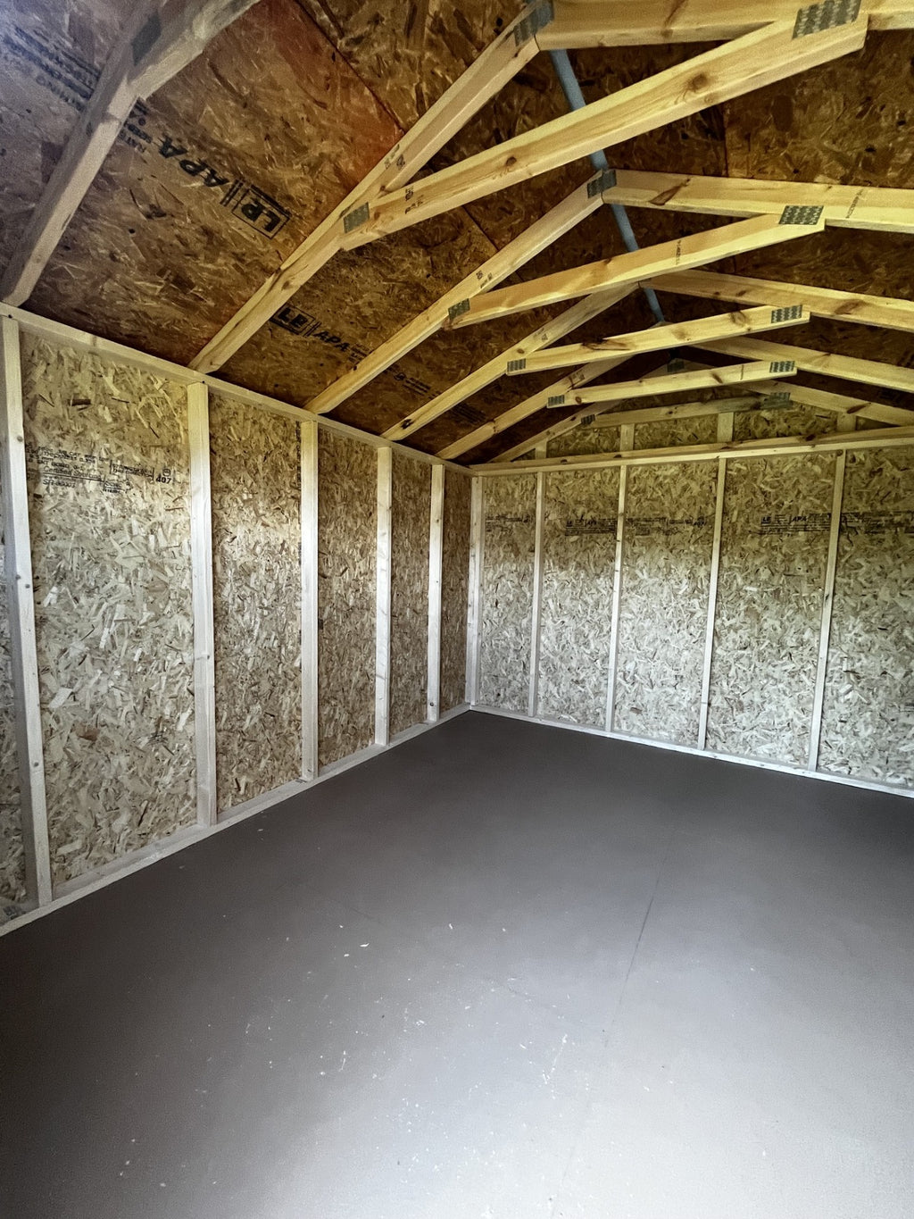 Outland Trailers 10x12 utility shed with double doors and sloped roof, ideal for storage and outdoor organization.