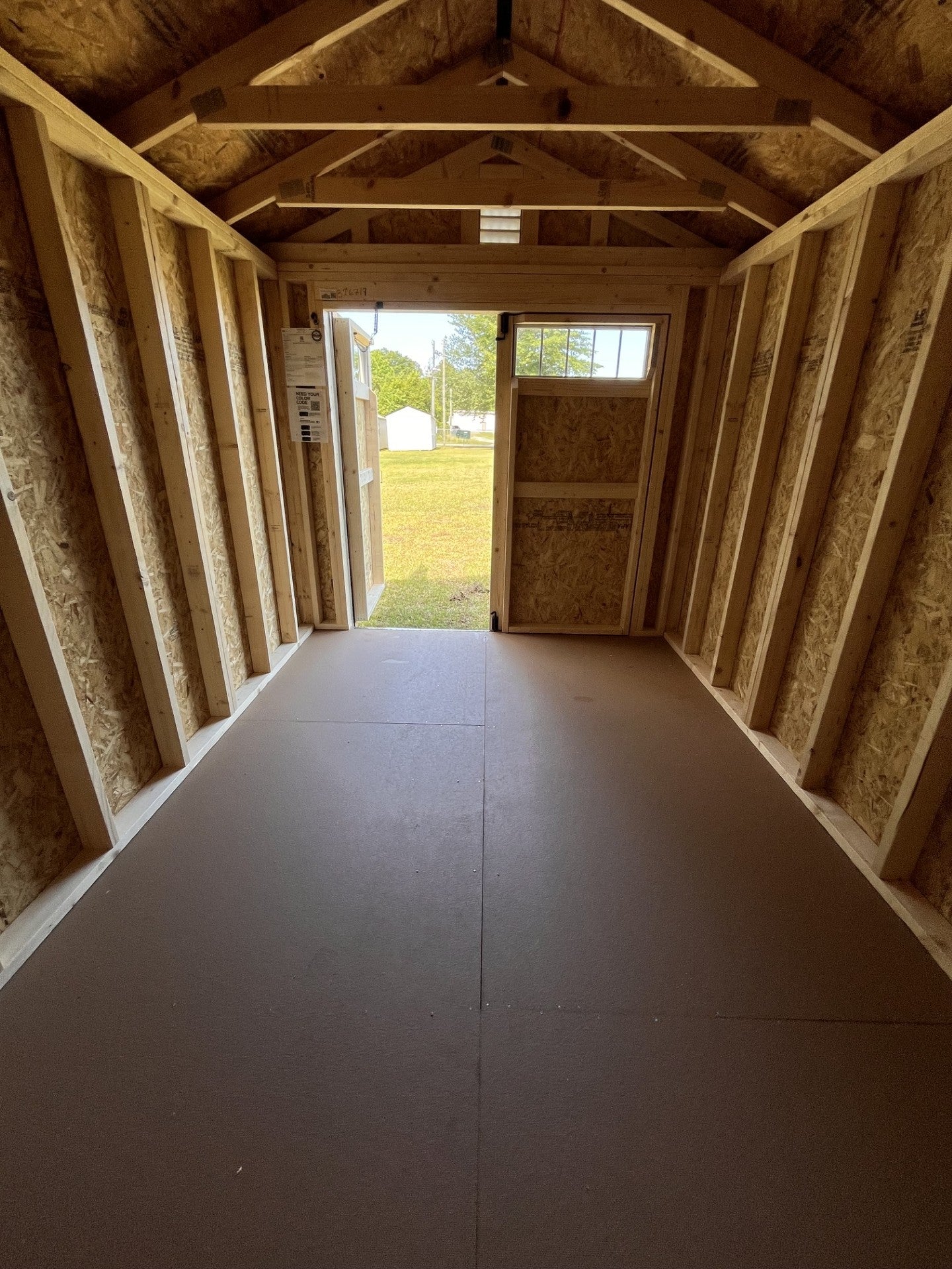 Outland Trailers 8x12 garden shed with wooden door and window, suitable for outdoor storage and gardening tools.