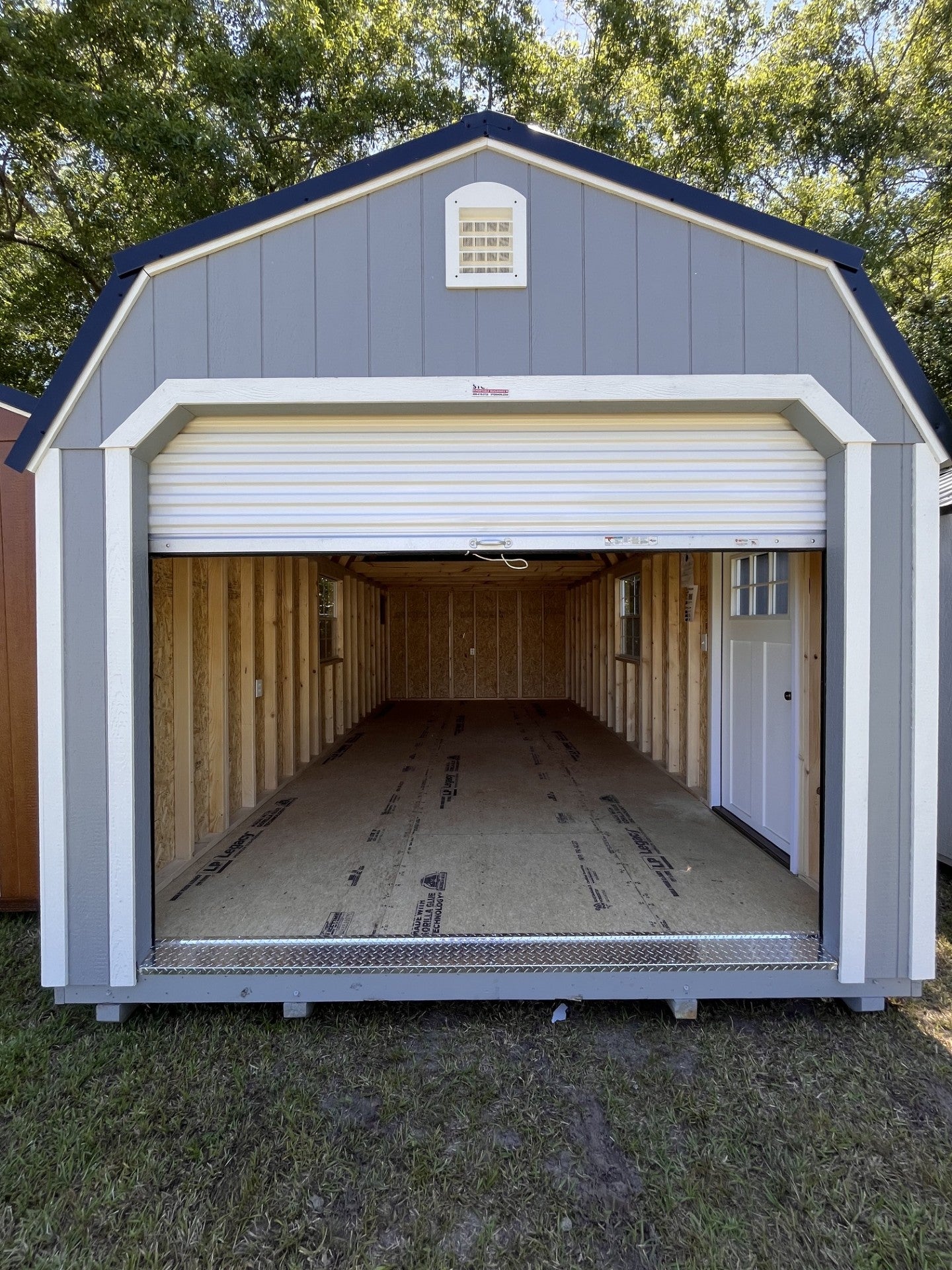Outland Trailers 12x24 lofted garage with raised roof, side door, and window, ideal for storage and workshop space.