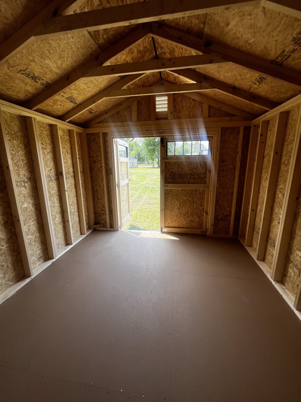 Outland Trailers 10x12 utility shed with sturdy metal walls and double doors, ideal for storage and outdoor organization.