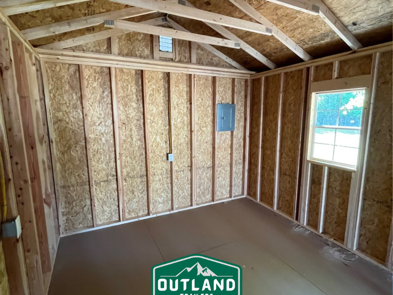 Outland Trailers 12x36 cabin trailer with wooden panels and metal frame, suitable for camping or tiny home conversion.