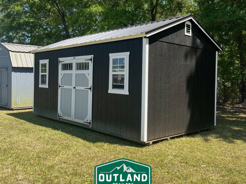 Used Outland Trailers 12x20 utility shed with metal walls and door, ideal for storage or workshop use.