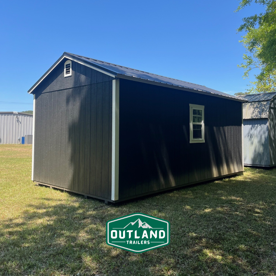 Used Outland Trailers 12x20 utility shed with metal siding and double doors, suitable for storage or workshop use.